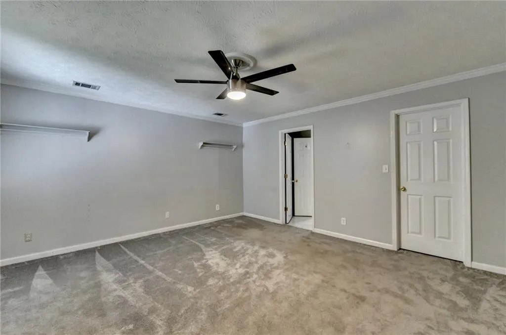 Unfurnished bedroom with ornamental molding, carpet flooring, baseboards, a textured ceiling, and a ceiling fan