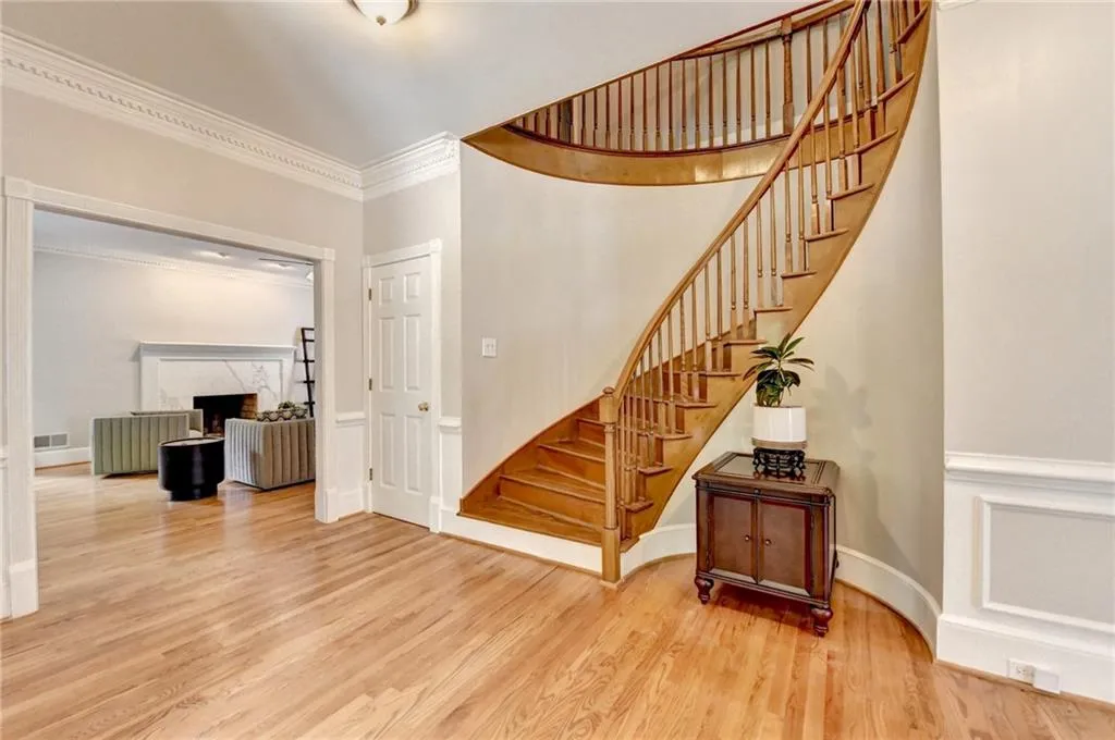 Entrance foyer with stairs, wood finished floors, ornamental molding, a fireplace, and baseboards