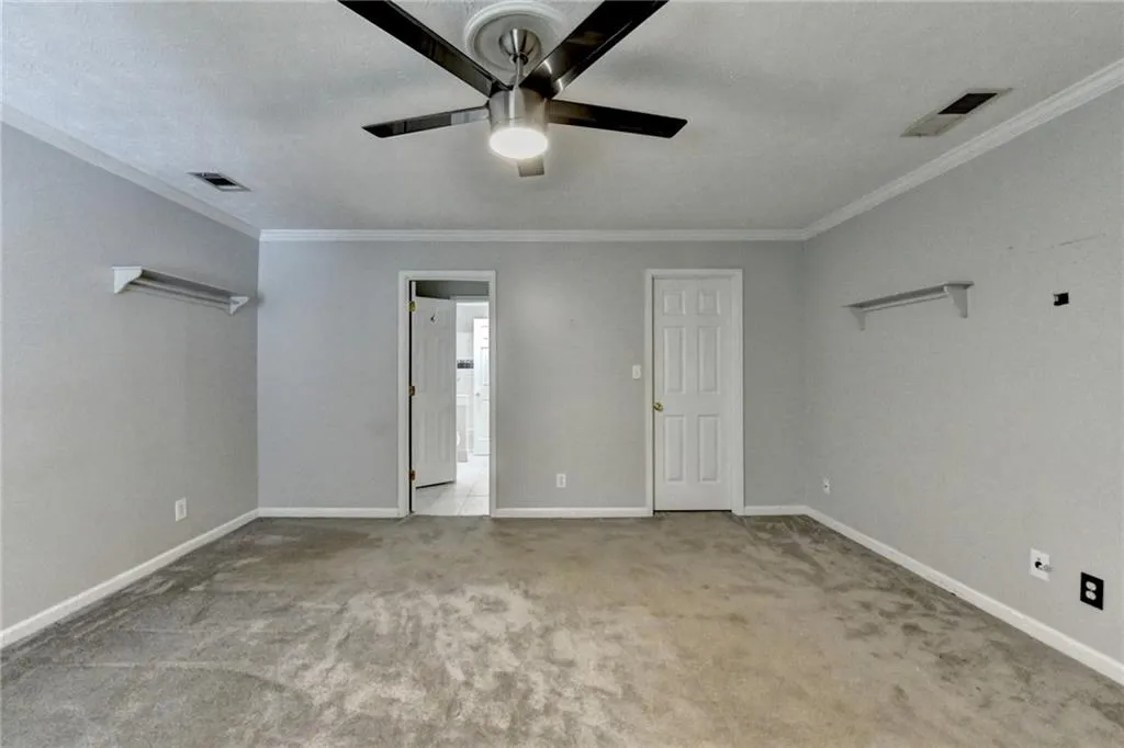 Unfurnished bedroom with carpet flooring, ornamental molding, baseboards, and a ceiling fan