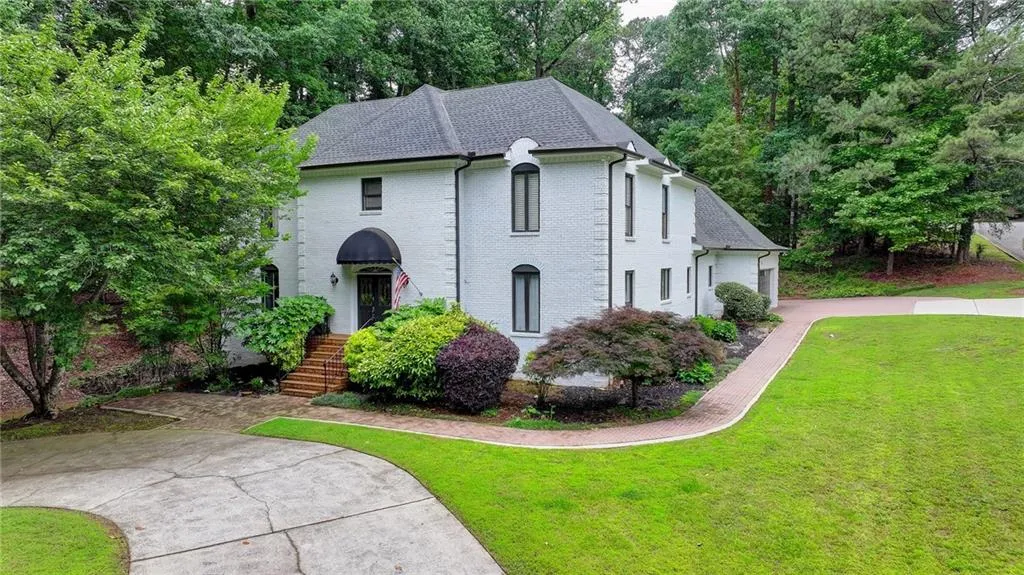 French country home featuring a front yard, brick siding, and roof with shingles