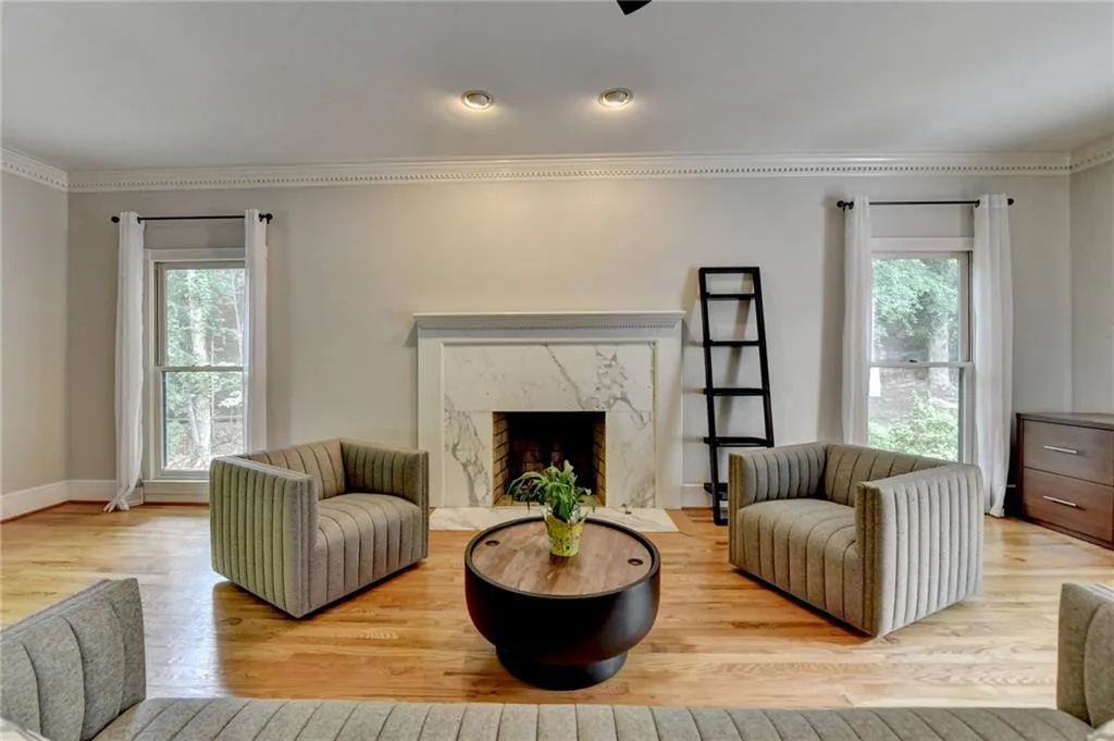 Living area featuring crown molding, healthy amount of natural light, wood finished floors, baseboards, and a fireplace