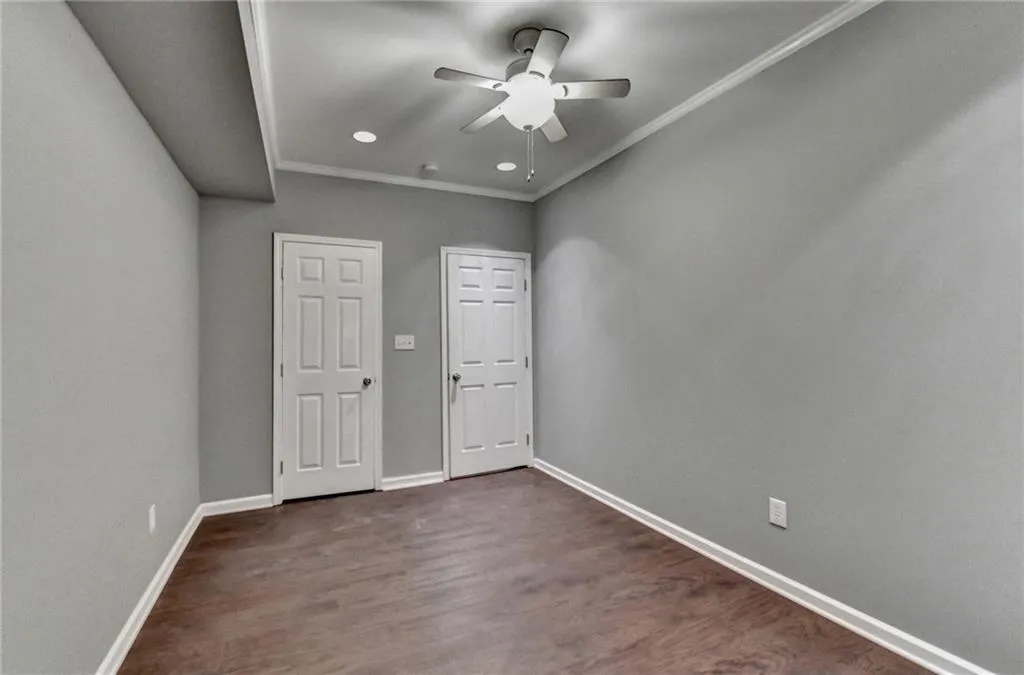 Unfurnished bedroom featuring baseboards, crown molding, dark wood-style floors, recessed lighting, and a ceiling fan