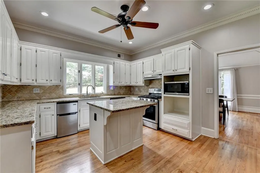 Kitchen with stainless steel appliances, a sink, plenty of natural light, a center island, and crown molding