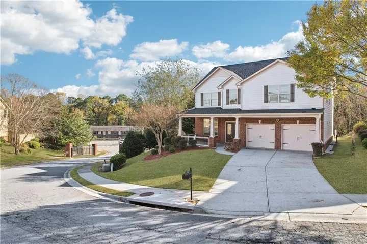 Two-story residence featuring a white siding and brick facade, a two-car garage, and a covered front porch