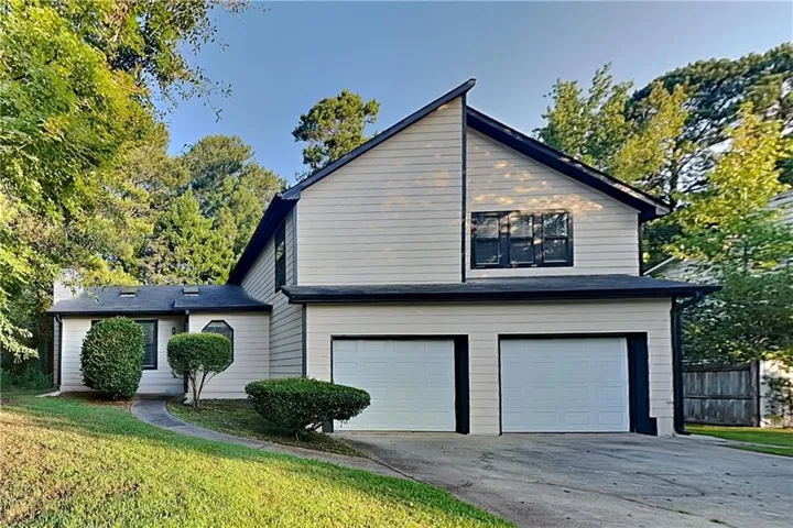 Two-story residence featuring light-colored siding and a dark roof