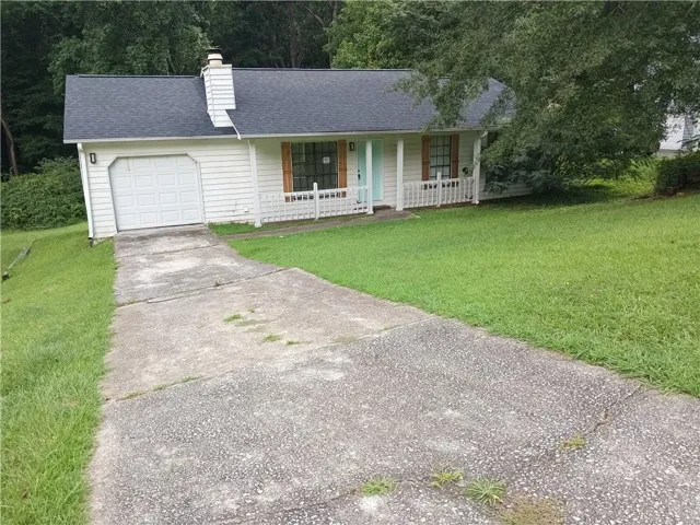White siding exterior with a single garage door, covered front porch, dark shingle roof, and a concrete driveway