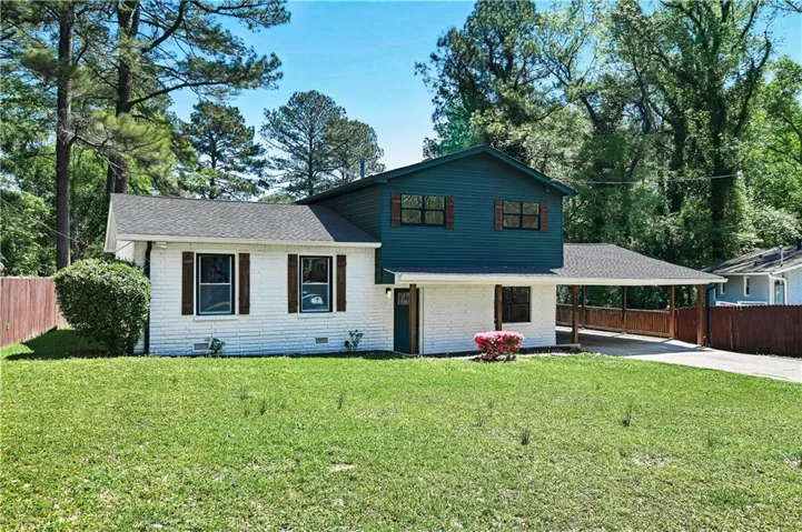 Split-level exterior featuring white painted brick and dark green siding