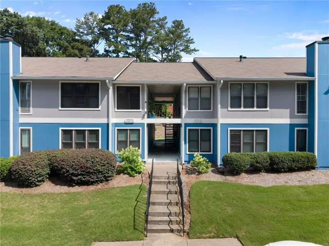 Multi-level building with blue and gray siding, brown shingle roofing, and white trim