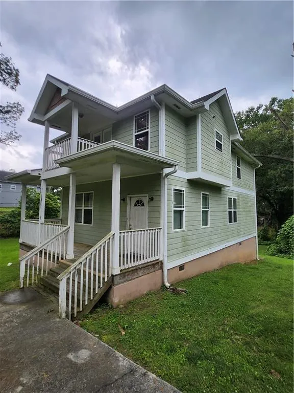 View of front of property featuring crawl space, a balcony, a front lawn, and a porch