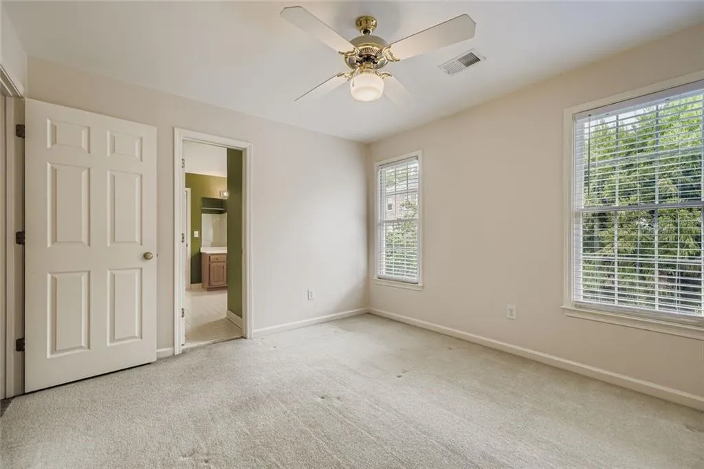 Unfurnished bedroom with carpet floors, ensuite bathroom, and a ceiling fan