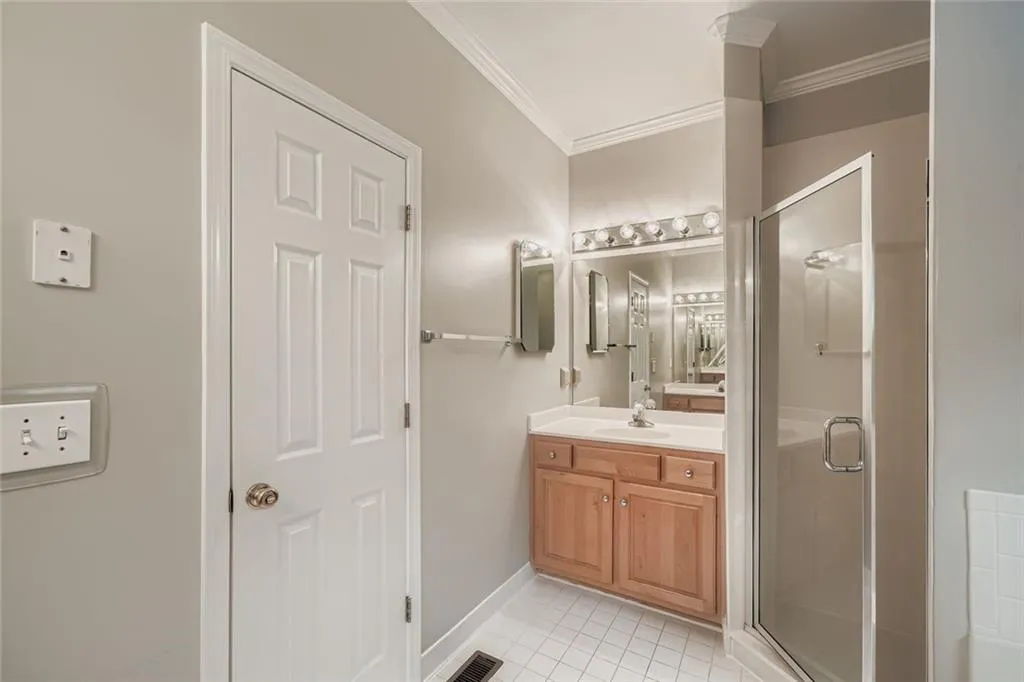 Bathroom featuring light tile patterned floors, vanity, a shower stall, and ornamental molding
