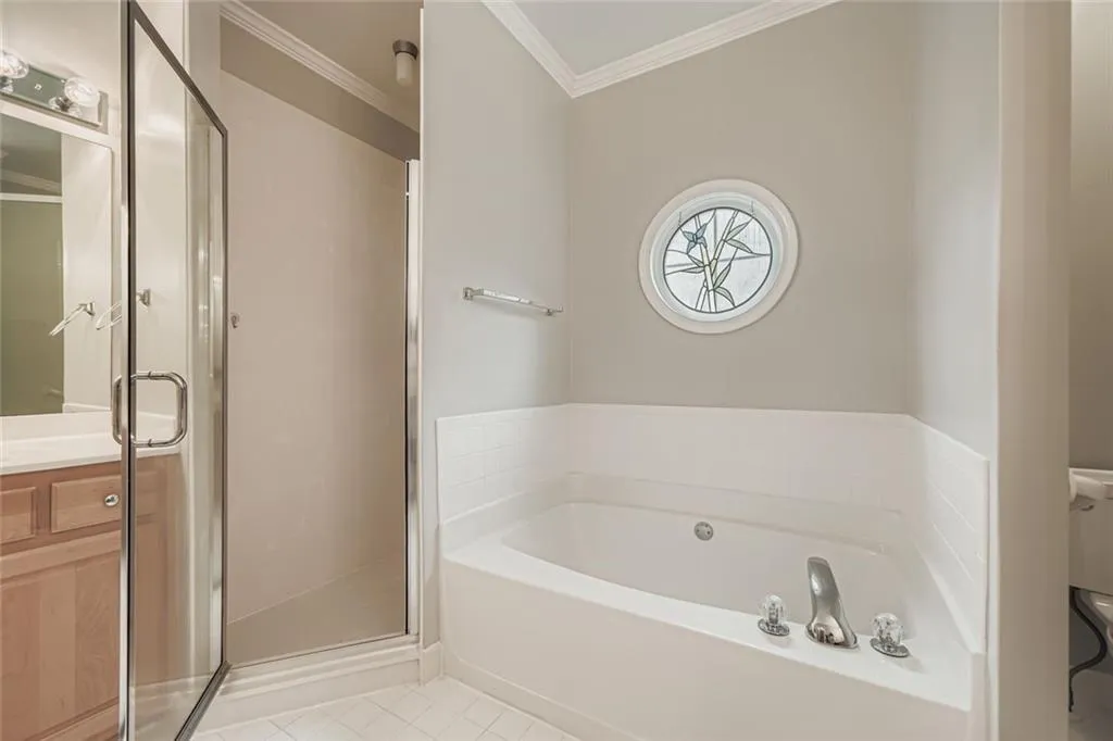 Bathroom featuring crown molding, a bath, a shower stall, light tile patterned floors, and vanity