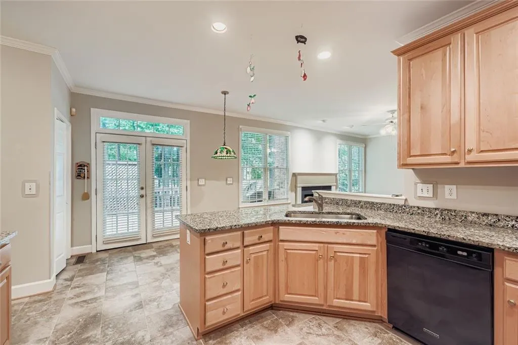 Kitchen featuring light brown cabinets, a peninsula, dishwasher, crown molding, and light stone countertops