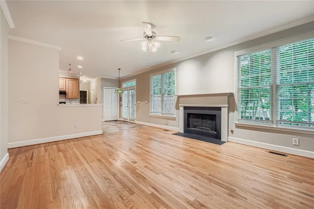 Unfurnished living room featuring ornamental molding, a ceiling fan, light wood-style flooring, and a fireplace with flush hearth
