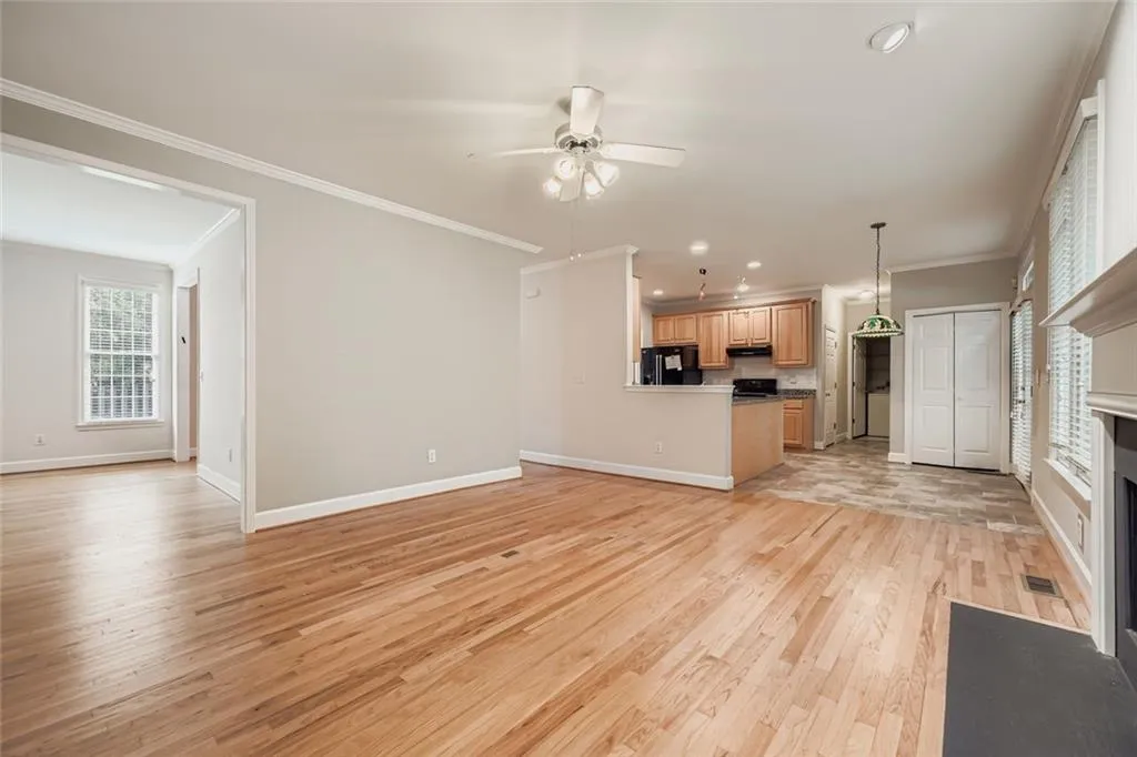 Unfurnished living room featuring light wood-style floors, crown molding, a ceiling fan, a fireplace with flush hearth, and recessed lighting