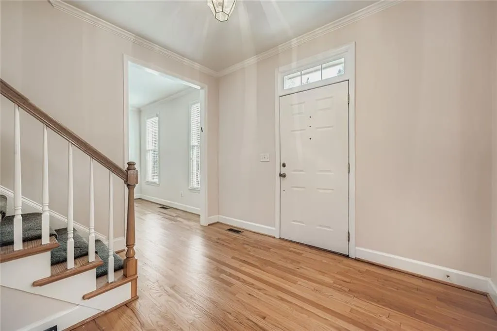 Entryway featuring stairway, crown molding, and light wood finished floors