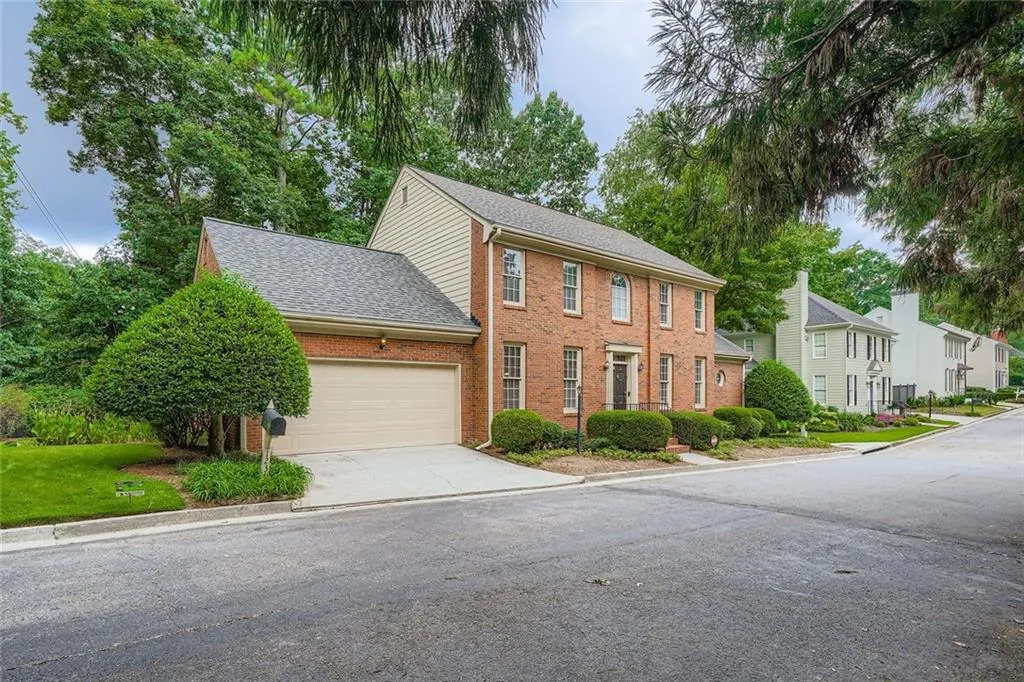 Colonial home featuring a garage, brick siding, roof with shingles, and driveway