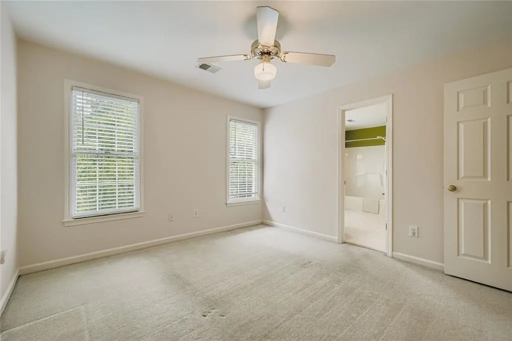 Unfurnished bedroom featuring carpet floors, ceiling fan, and connected bathroom
