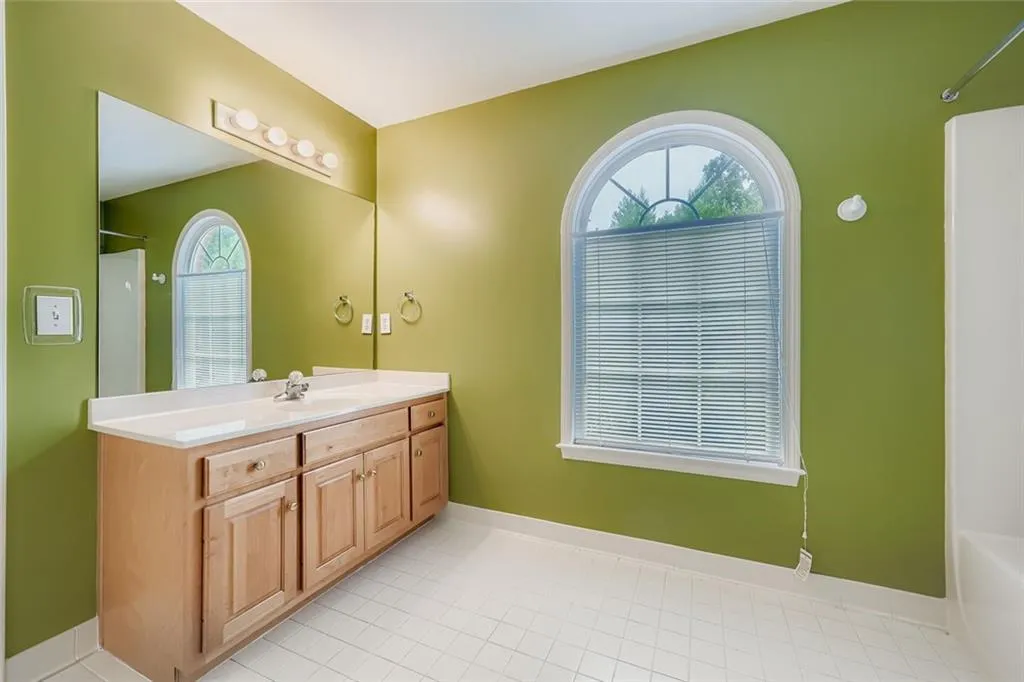 Full bathroom with vanity, healthy amount of natural light, and light tile patterned flooring