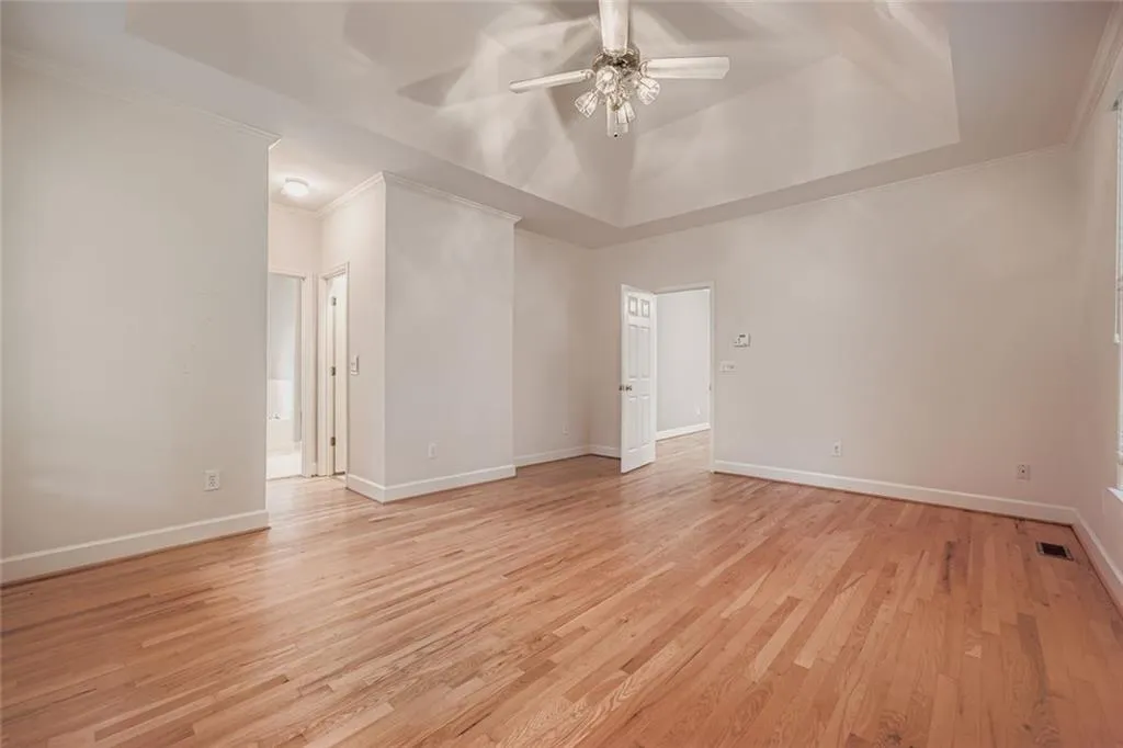 Spare room featuring crown molding, a raised ceiling, light wood-type flooring, and a ceiling fan