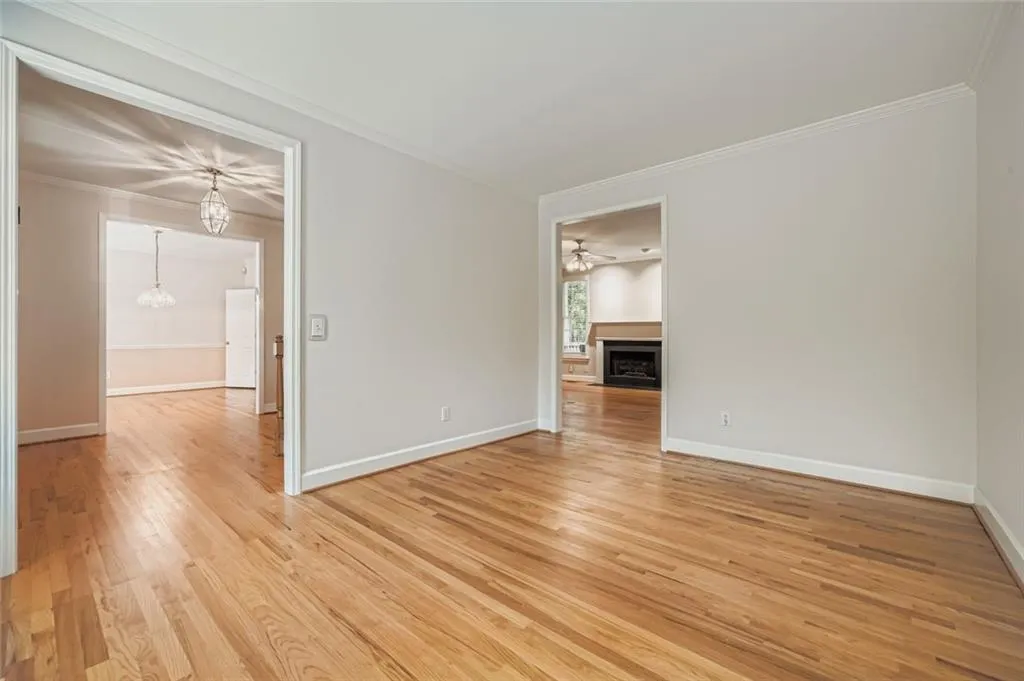 Spare room featuring crown molding, light wood finished floors, a fireplace, and a ceiling fan