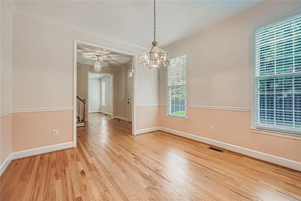 Unfurnished dining area with ornamental molding, light wood finished floors, a chandelier, and stairs