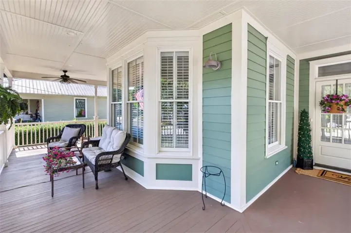 Welcoming covered porch with a ceiling fan, plank flooring, and a bay window