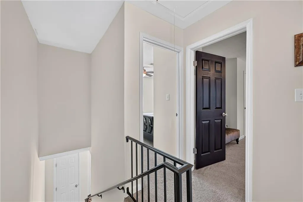 Interior hallway featuring black six-panel interior doors, metal stair railing, and carpeted flooring