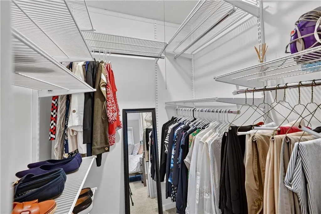 Walk-in closet featuring multi-tiered white wire shelving and integrated garment rods