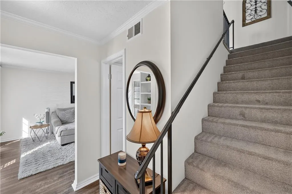 Staircase featuring wall-to-wall carpeting and a metal railing with vertical balusters