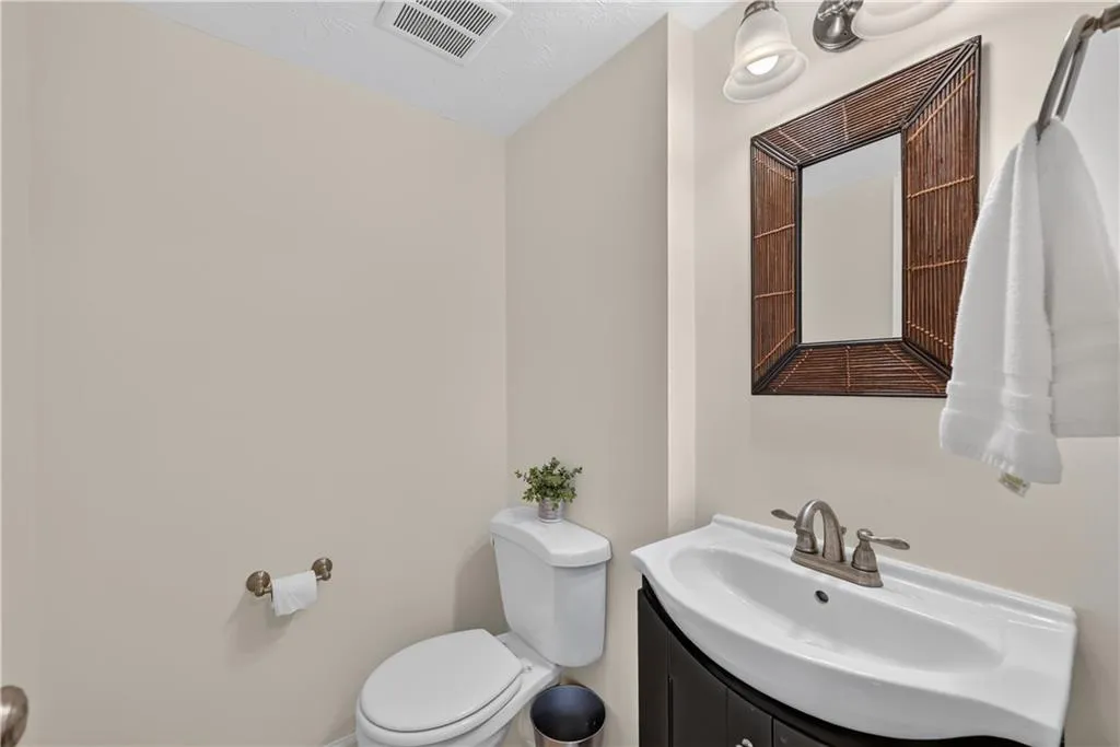 Wall-mounted vanity with a porcelain sink, integrated metal faucet, and decorative framed mirror paired with brushed nickel lighting fixtures
