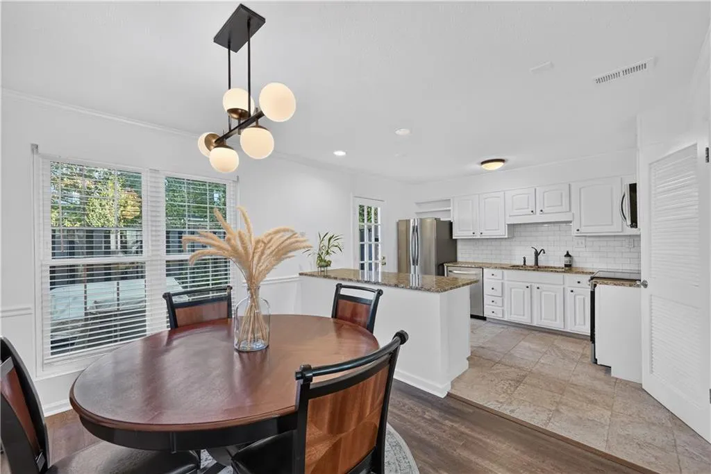 Modern pendant light fixture, stone-surface breakfast bar, white shaker-style cabinetry, subway tile backsplash, and stainless-steel appliances
