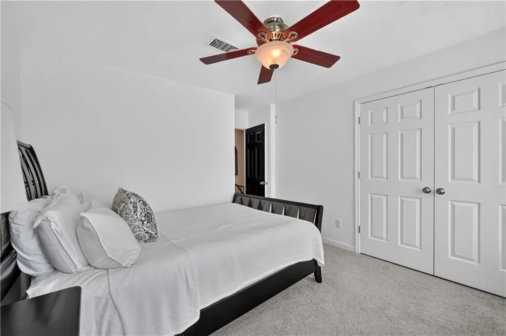 Neutral-toned carpeting, ceiling fan with integrated lighting, and double-panel closet doors