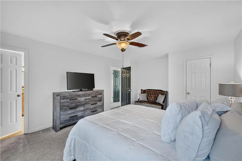 Bedroom featuring neutral wall paint, carpeted flooring, a ceiling fan with integrated lighting, and multiple interior paneled doors