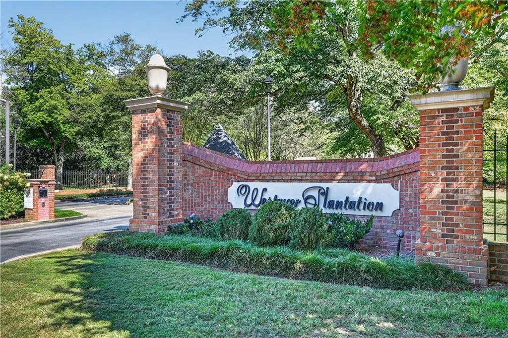 Brick masonry monument entrance featuring decorative stone caps and manicured shrubbery