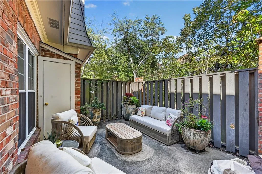 Private outdoor patio featuring a concrete surface, red brick exterior wall, and vertical wood privacy fencing