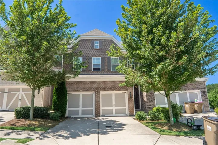 Brick exterior with dormer window, shutters, two-car garage, and established front landscaping