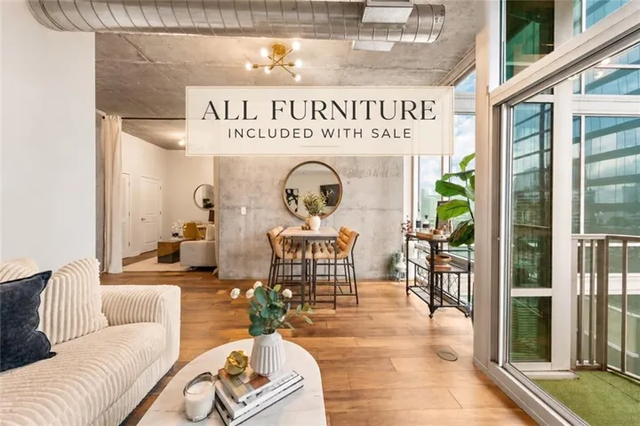 Hardwood-style flooring, exposed concrete ceiling with ductwork, expansive glass doors, and a built-in balcony