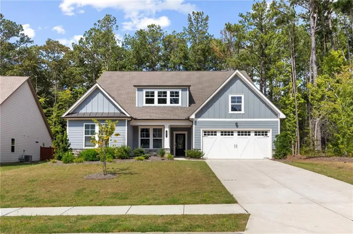 Exterior featuring light blue siding, a dormer window, a two-car garage, and a concrete driveway