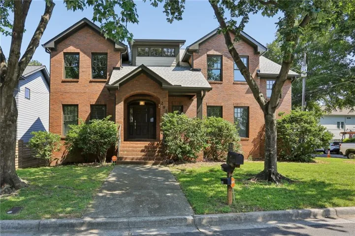 Brick exterior with an arched entryway, gabled rooflines, dark-framed windows, and mature landscaping