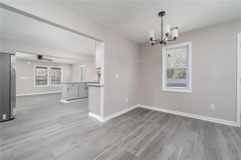 Unfurnished dining area featuring healthy amount of natural light, light wood-style flooring, and a chandelier