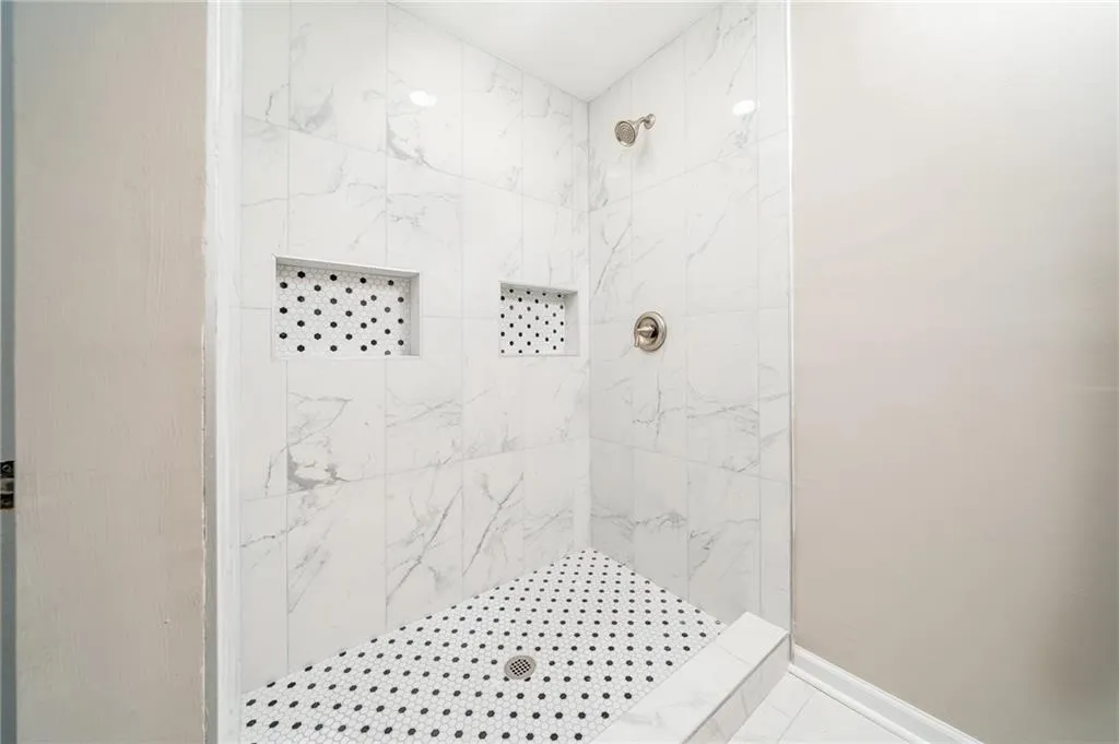 Full bath with tiled shower and baseboards