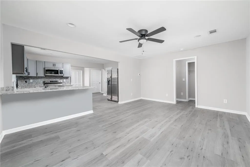 Unfurnished living room featuring light wood-style flooring, a ceiling fan, and recessed lighting