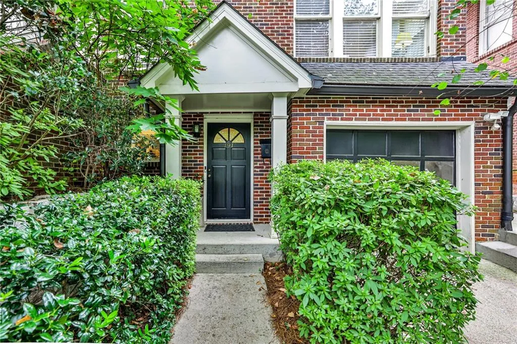 Brick exterior with a covered entry, dark paneled front door, and an attached garage