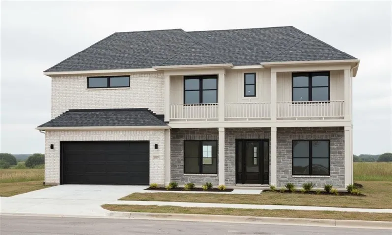 Two-story residence featuring light brick and stone masonry, a dark shingle roof, a black garage door, and black-framed windows