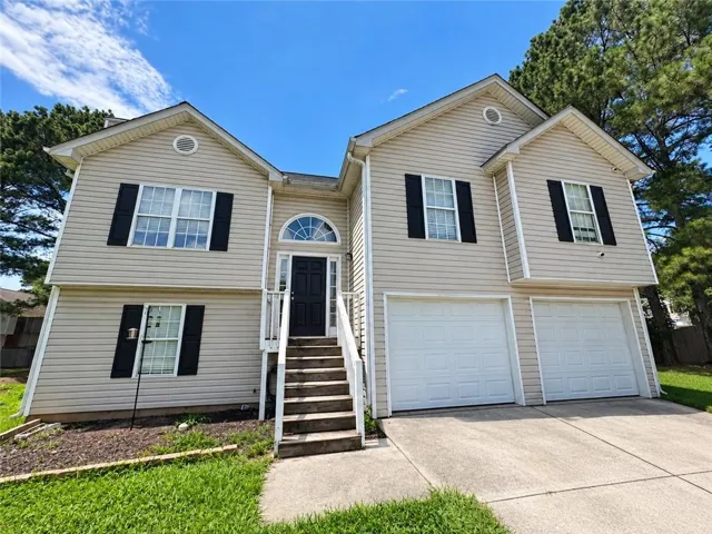 Two-story exterior with light-colored siding, contrasting black shutters, an arched transom window above the entry door, and a two-car garage with white panel doors