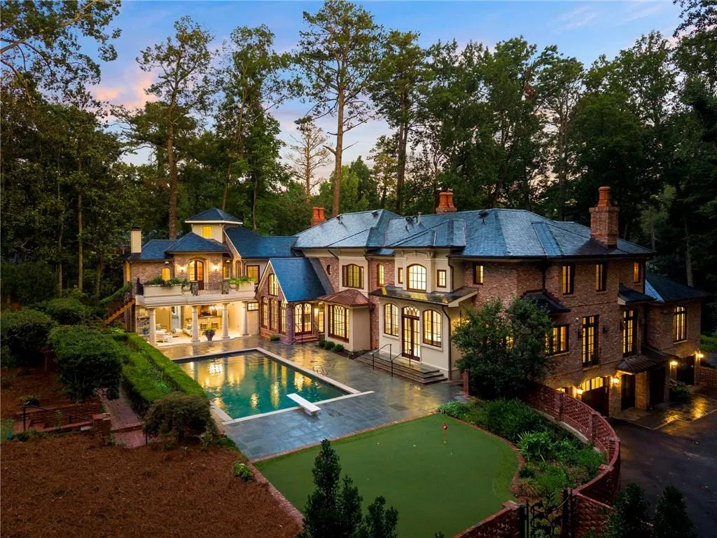 Expansive brick and stucco residence featuring a multi-level design, a large swimming pool with diving board, a private putting green, and mature surrounding landscaping