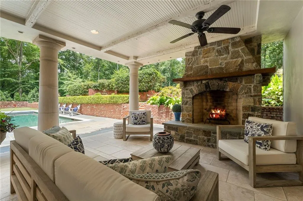 Covered patio featuring a stone fireplace with a wood mantle, a ceiling fan, and recessed lighting