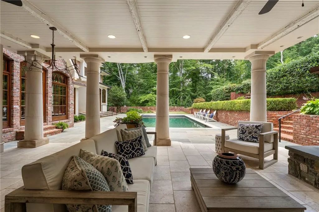 Covered outdoor patio featuring stone tile flooring, structural columns, and a beadboard ceiling with recessed lighting