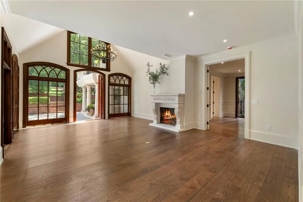 Spacious room featuring vaulted ceilings, wood-finish flooring, and a carved stone fireplace